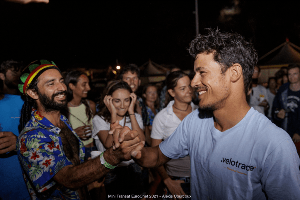 Close-up night shot of Velotrade skipper Brieuc shaking hands with a guy post the race.