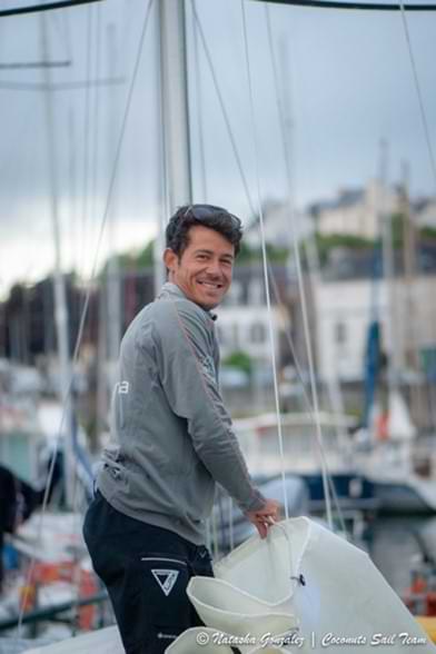 Portrait shot of Velotrade skipper Brieuc Lebec on the sailing boat holding the sail.