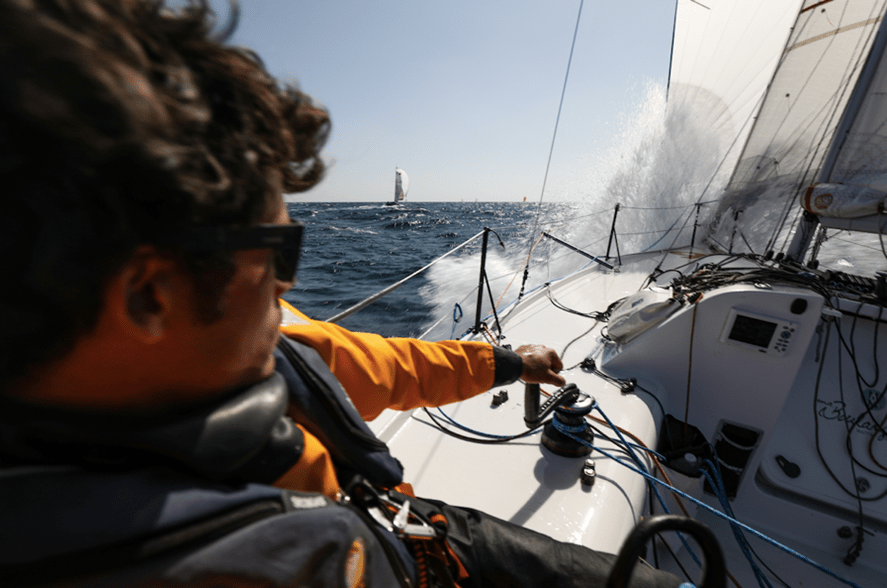 Closeup back shot of Velotrade skipper Brieuc Lebec driving the sailing boat.